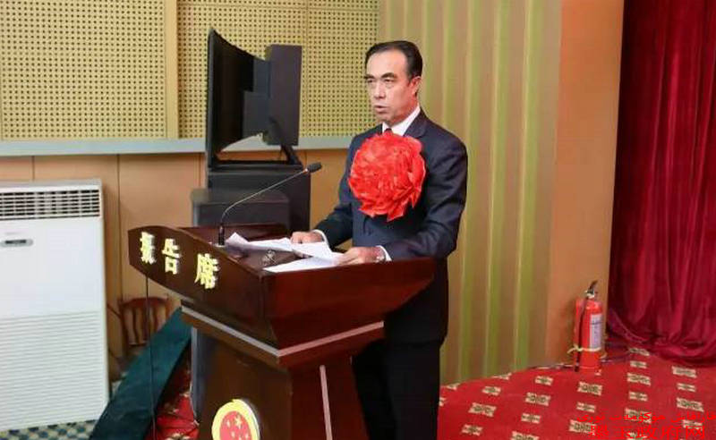 马合木提·吾买尔江左手抚按《宪法》,右手握拳上举,面对国徽,向宪法