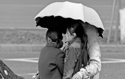 雨下得急,三人挤在一把伞下避雨 新文化记者 蒋盛松 摄
