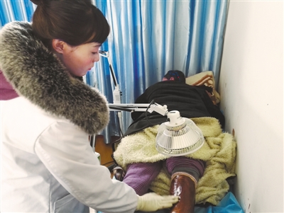 图为琼结县人民医院卫生员央金卓玛正在为关节炎患者进行烤电针灸治疗