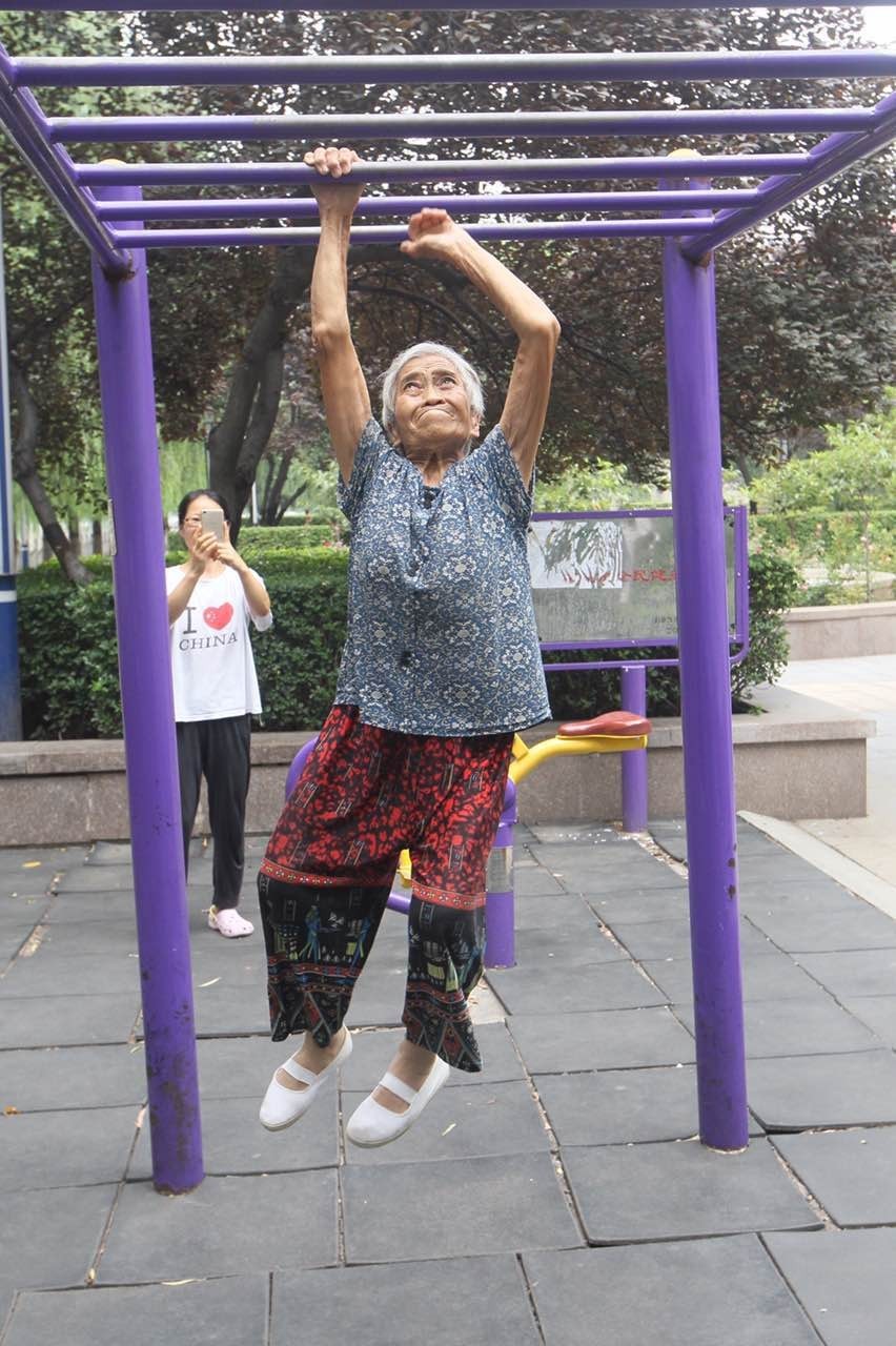 双手攀梯漫步自如一位年轻人向老人竖起了大拇指崔俊英老人一直保持着