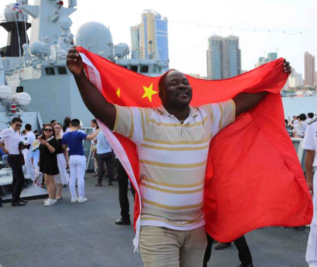 当地时间8月18日,坦桑尼亚友人在参观中国海军军舰时,披着中国国旗