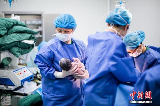 资料图：医生怀抱着一名刚出生婴儿。刘梦璇 摄