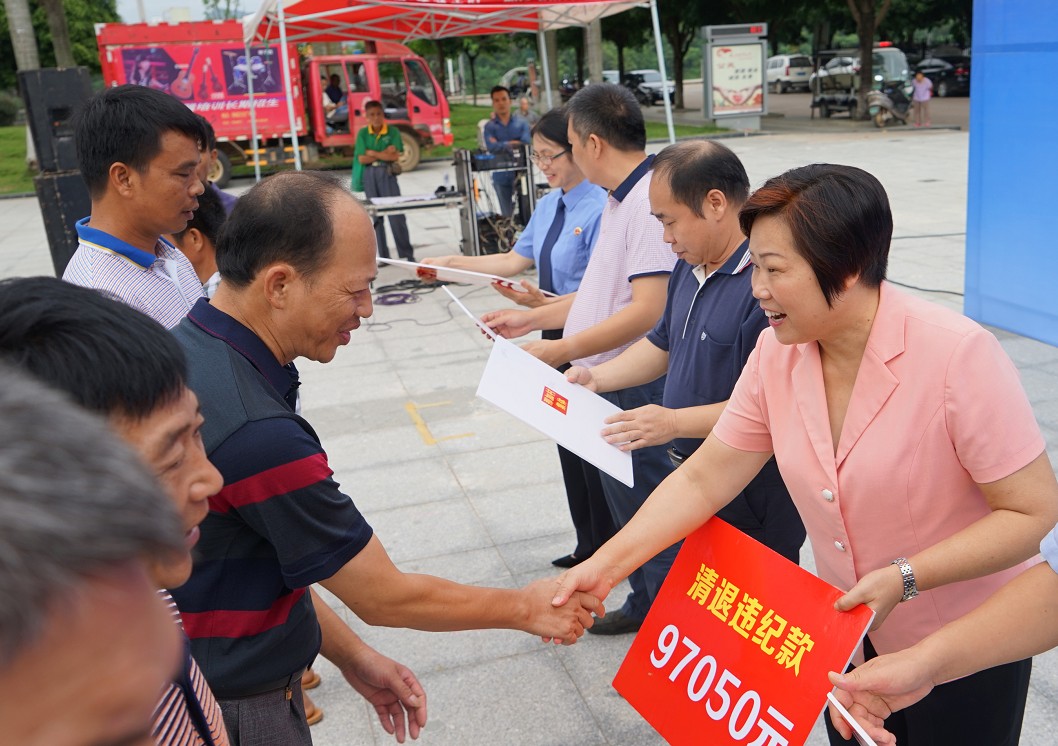 崇左市纪委常委,市纪委书记梁日端(右一)将清退款发放给农户