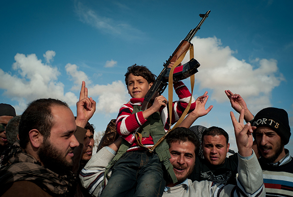 当地时间2011年3月21日,利比亚阿季达比亚,反对派士兵的孩子拿着ak-47