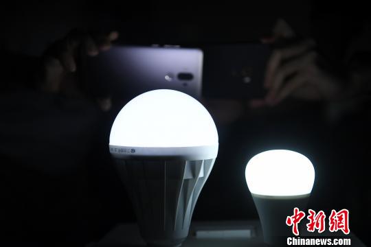 图为学生用手机摄像头拍摄灯泡的方式来快速鉴别led灯的真伪. 陈超 摄
