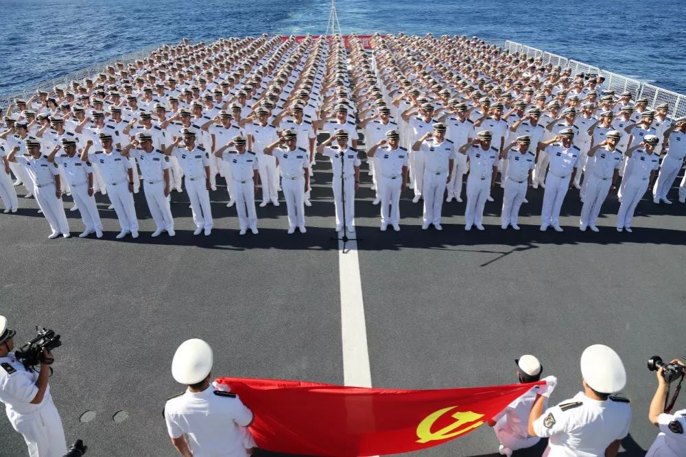 中,全体官兵向党旗敬礼,在出访指挥员严正明少将的带领下重温入党誓词