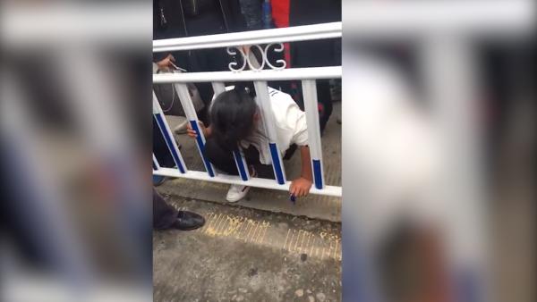 女子翻护栏过马路,头被卡栏杆