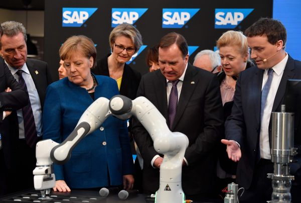 德国总理默克尔（左二）在汉诺威工业博览会上观看一只机械臂如何工作（法新社）