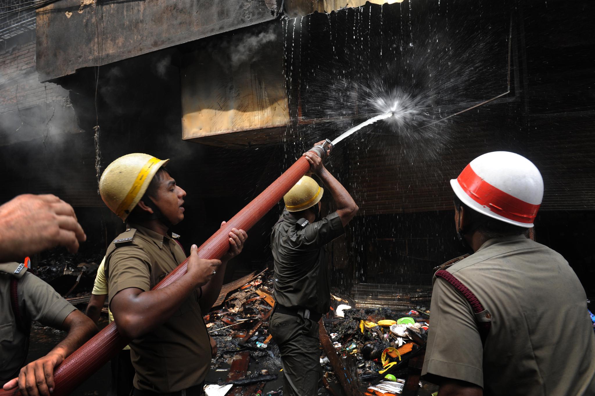 9月16日,消防员在印度加尔各答发生火灾的大楼外灭火.