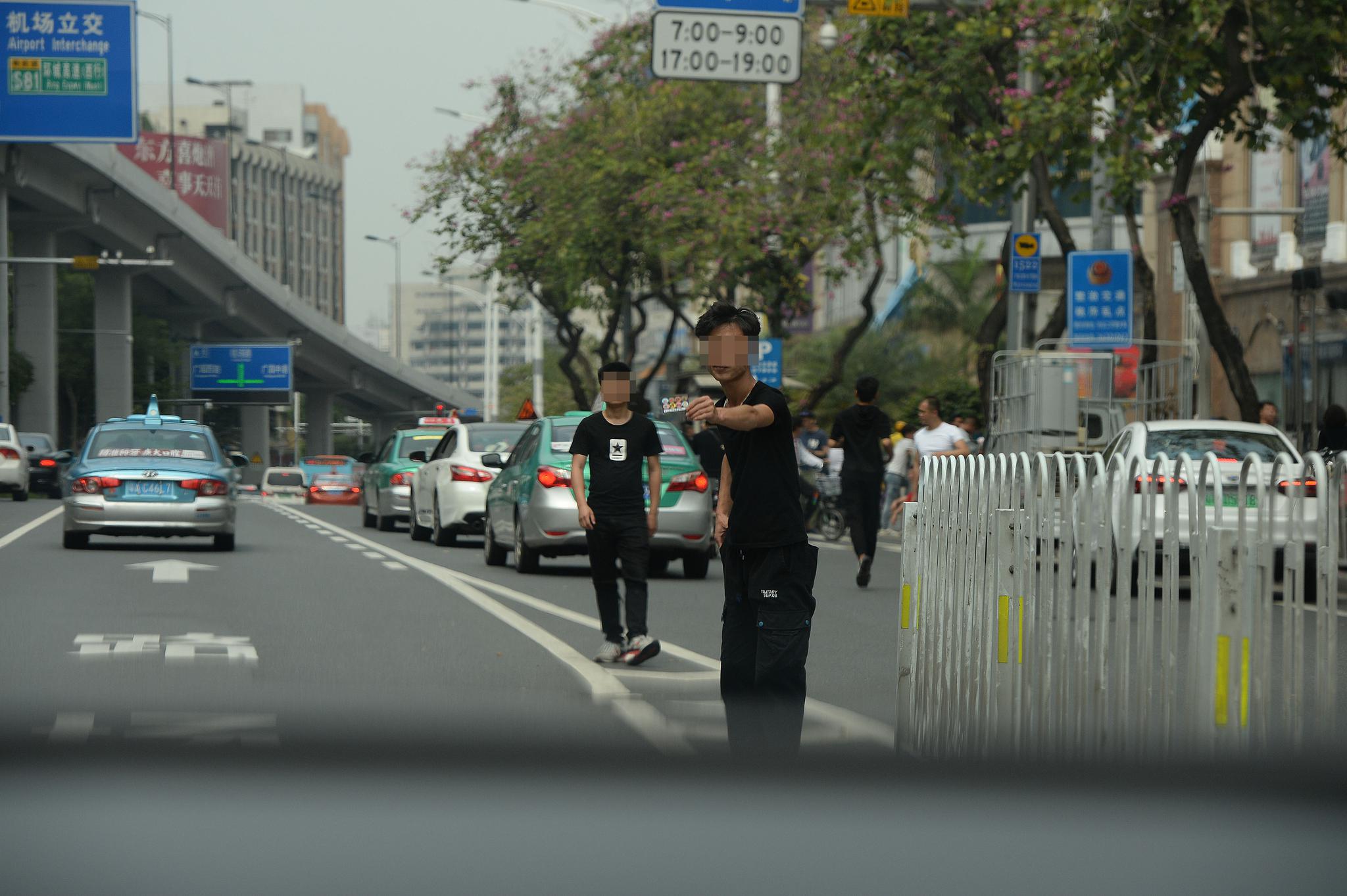 3月17日下午,广州市白云世界皮具贸易中心门前的解放北路,一名拉客人员在机动车道上往一辆私家车内递名片。 新京报记者 吴江 摄