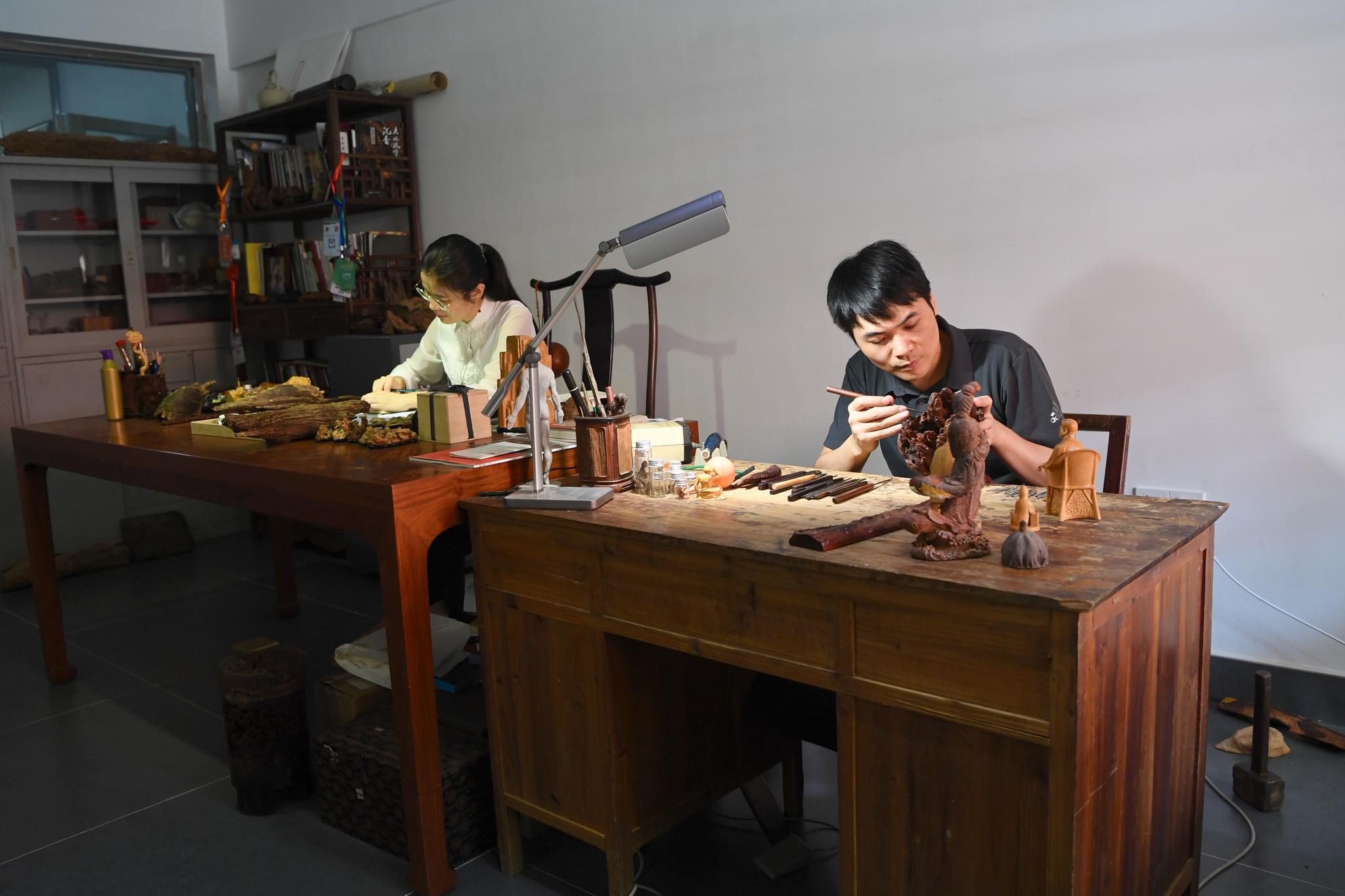 10月23日,林建军(右),陈琴夫妇在福建莆田的工作室进行木雕创作.