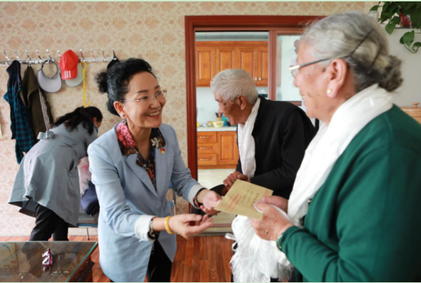 图为巴桑卓玛为十八军老战士德钦娜姆送上慰问金