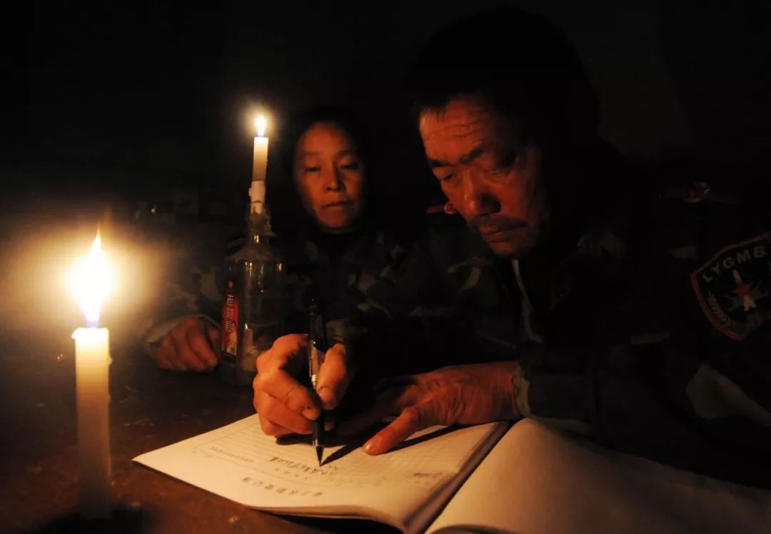 王继才夫妇在烛光下写每天都要记录的巡岛日志(2011年11月1日摄)。新华社发(沈鹏 摄)