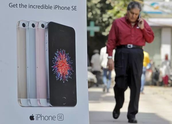▲资料图片：印度新德里，一名男子走过苹果手机广告牌。（新华社/路透社）