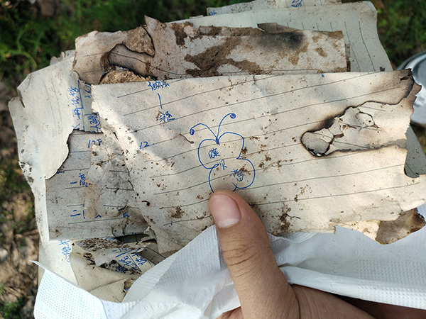 2017年8月5日，天津，在距发现李文星遗体500米处的一个露天传销窝点，写有“蝶贝蕾”字样的笔记散落在地上。视觉中国 资料图