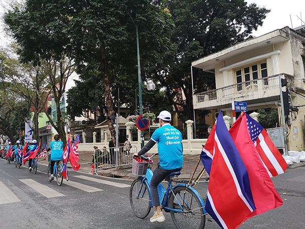 身穿蓝色制服，头戴白色帽子的大学生志愿者们，正骑着悬挂着美越朝三国国旗的自行车在河内街头环游，为即将到来的“金特会”造势。 李禾悦 供图