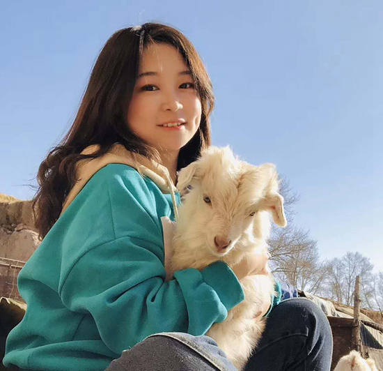 娜仁抱着家里的羊。