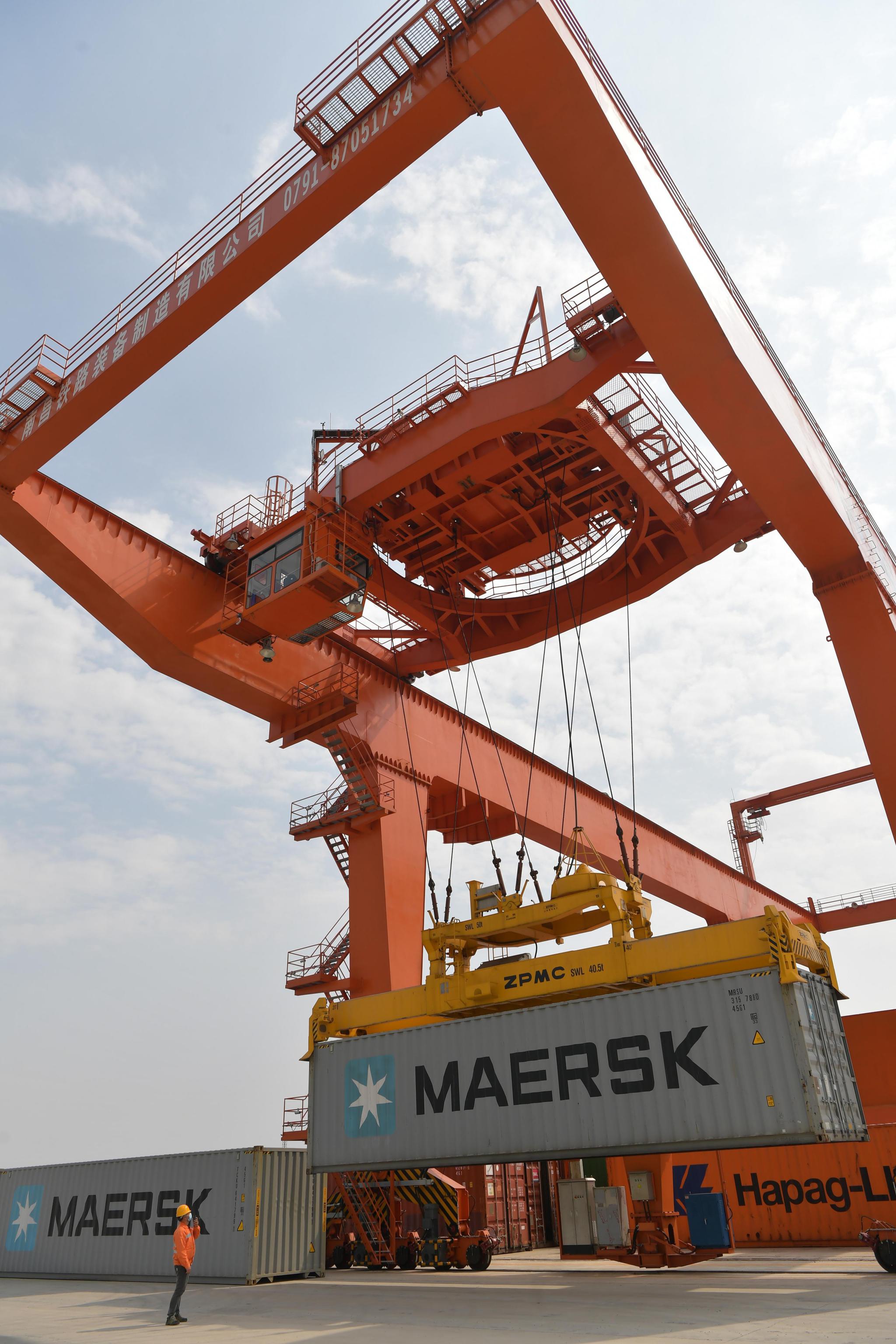 在江西省南昌县向塘铁路口岸,工作人员在指挥吊起集装箱(4月6日摄