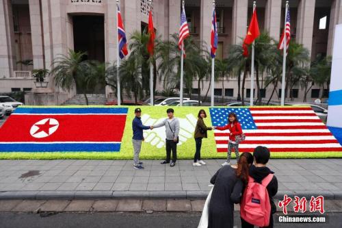 当地时间2月26日，越南首都河内，民众在“金特会”造型花坛前握手合影。朝美领导人第二次会晤将于2月27日-28日在越南首都河内举行。中新社记者 富田 摄