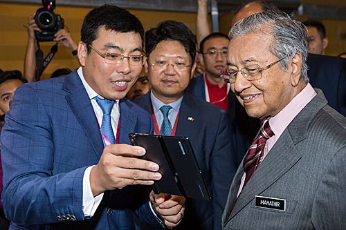  在马来西亚普特拉贾亚，马来西亚总理马哈蒂尔（右）在5G技术展上听取华为5G智能手机的介绍。（新华社）