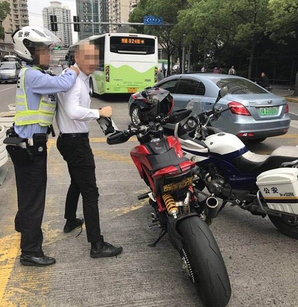 引擎轰鸣声极响的摩托车在经过高考考点附近时,被静安交警支队民警拦