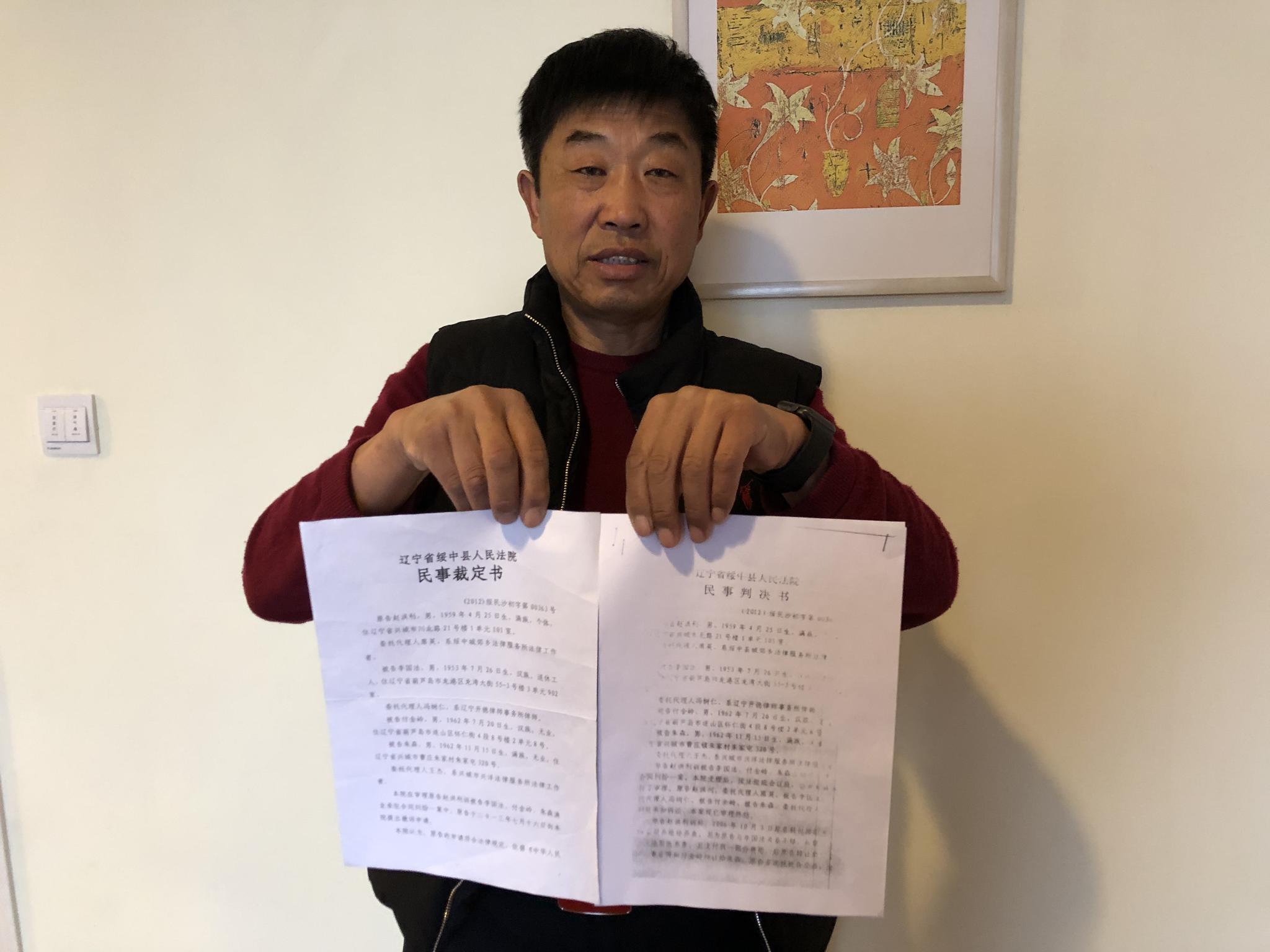 　赵红利拿着同一案号的民事裁定书和民事裁定书。新京报记者卢通摄。