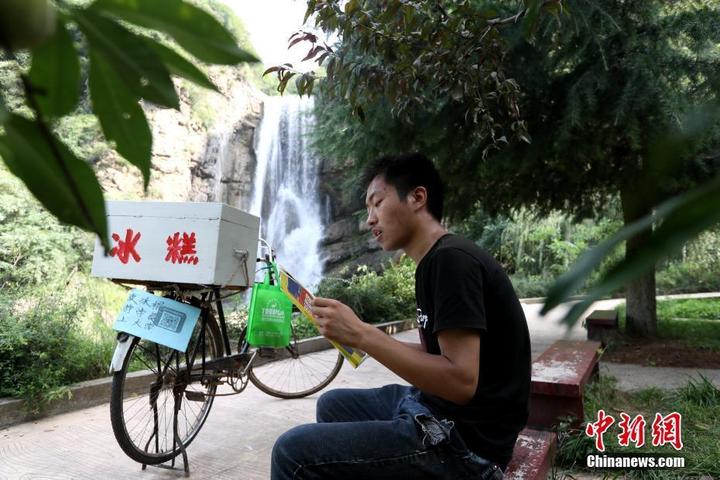 图为闲暇之时,小赵坐在石板上背英语.