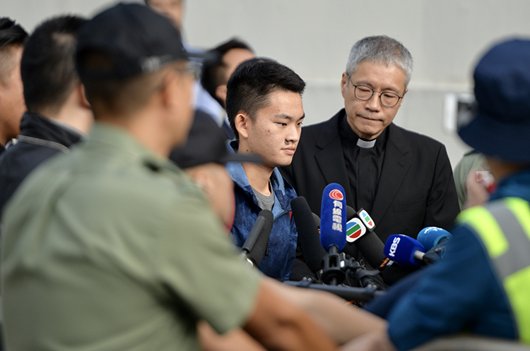 10月23日9时许，陈同佳在牧师陪同下走出香港新界壁屋惩戒所，表情严肃。 新京报特派香港报道组 摄