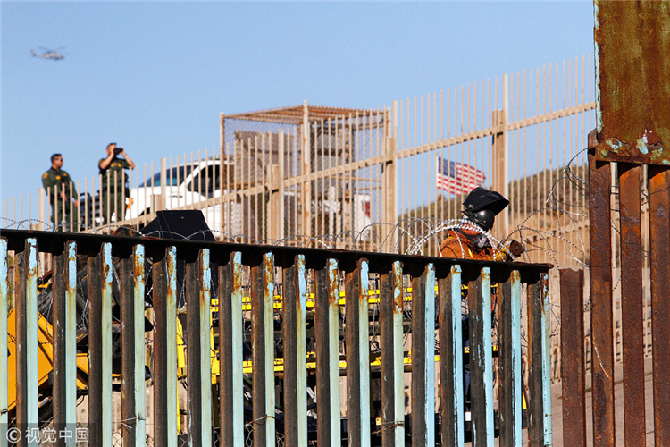 咫尺天涯!中美洲移民攀爬美墨边境墙眺望美国