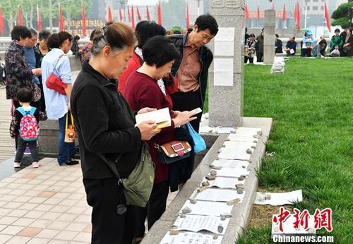 资料图：河北石家庄相亲广场，父母正在帮孩子看征婚信息。中新社记者 翟羽佳 摄