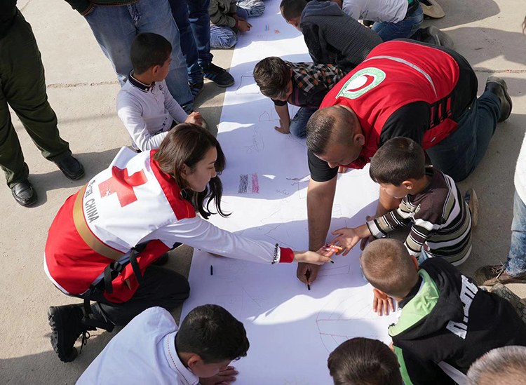 伊拉克首都巴格达，中国红十字会项目组工作人员、伊拉克红新月会工作人员与聚居区孩子一起画画。