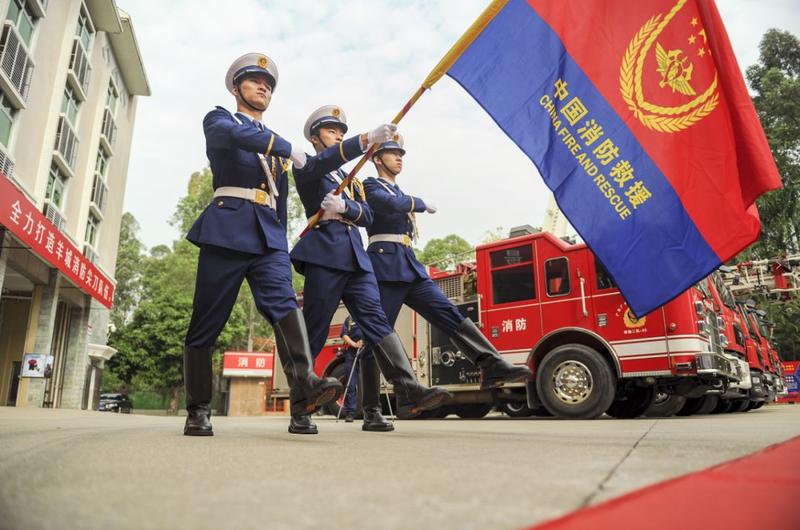 胸戴光荣退出绶带的全体退出消防员昂首挺立,整齐地向队旗庄严敬礼