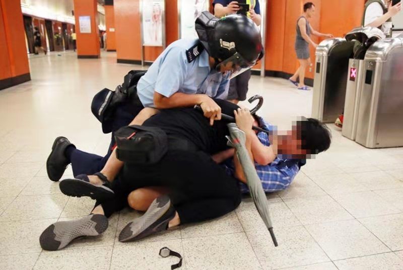 身穿蓝色格子衫的香港市民协助港警制服暴徒。来源：港媒