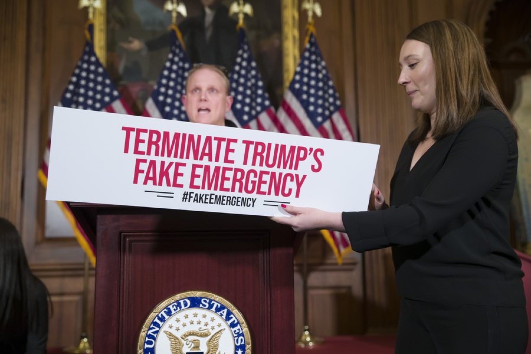 当地时间2月26日晚，众议院工作人员挂上标牌：终止特朗普虚假的紧急状态。