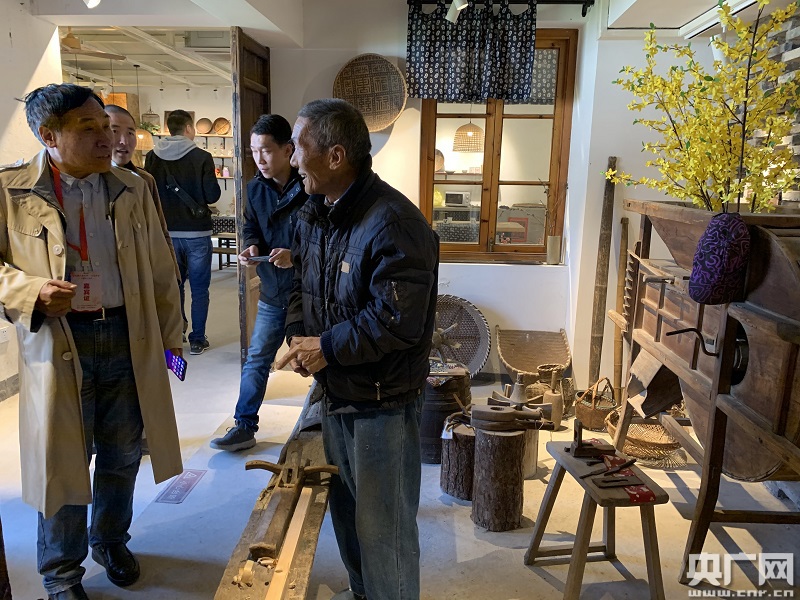 梅林村匠心铺内的本地工匠正向游客展示其所做的手工艺品（央广网记者 孙冰洁 摄）