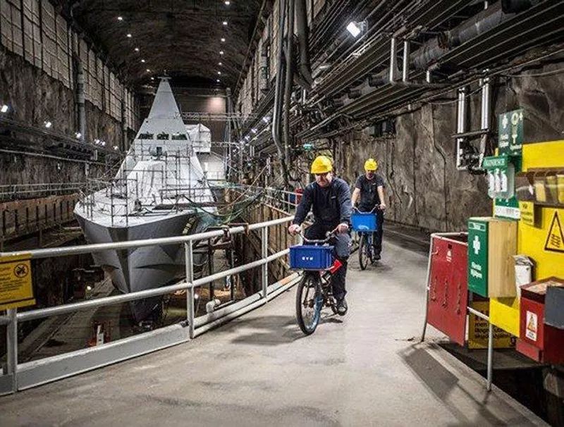 ▲图为穆斯克海军基地地下船坞内，两名瑞典海军士兵骑自行车从一艘维斯比级隐身护卫舰旁驶过。（瑞典国防部网站）