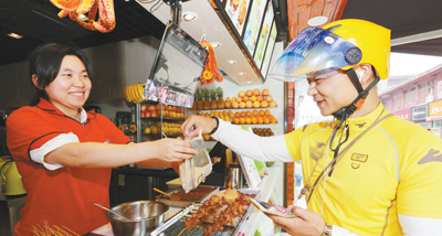 湖北省襄阳市，一位快递小哥正在商家取顾客在外卖平台上预订的餐品。人民视觉