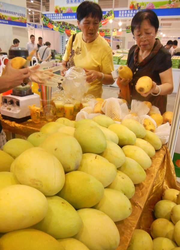 2014年，两名大陆居民在海峡两岸农牧渔产业交易会上选购台湾水果。 新华社资料图