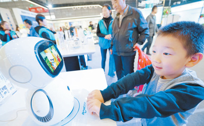 在中国国际家用电器暨消费电子博览会上，小朋友与智能机器人互动。 许庆勇摄（人民视觉）