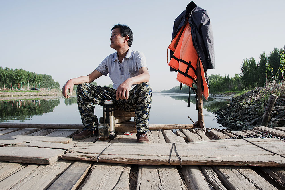 摆渡人李国新,在没有客人的时候在船上休息.