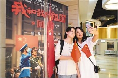 10月6日，重庆市市民在沙坪坝电影院与电影《我和我的祖国》海报合影。孙凯芳摄（人民图片）