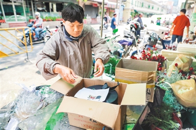 在泰国曼谷帕空鲜花市场的一家花店，快递人员将由云南鲜花制作成的花盒取走配送。 新华社记者 张可任摄