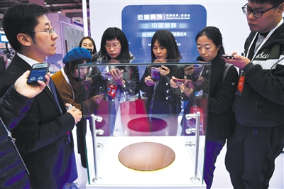 工作人员在介绍5G滤波器芯片晶圆,从晶圆上可以切割出众多块n77滤波器。