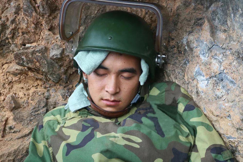作业间隙，队里组织休息，杜富国在雷场外地上穿着防护服就睡着了。杨萌 摄