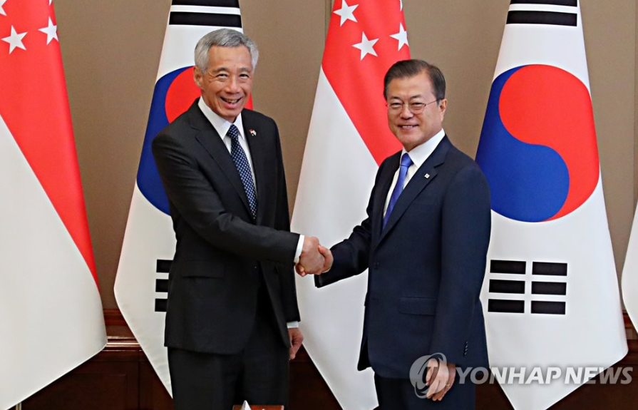  23日，在青瓦台，韩国总统文在寅同到访的李显龙握手合影。（韩联社）