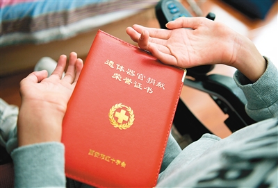 张为用嘴叼着笔签订器官捐献志愿登记表.