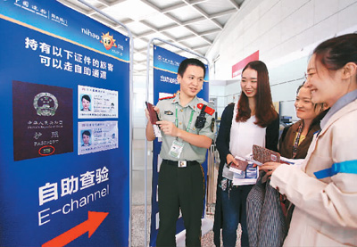 旅客在扬州泰州国际机场边检站民警指导下自助通关。孟德龙摄 （人民图片）