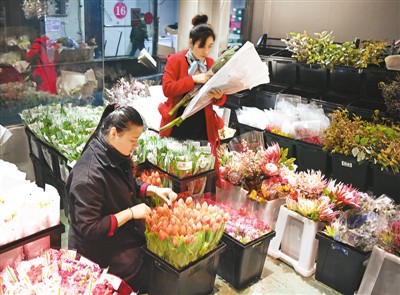 臧晶晶（左）在河南郑州小马进口鲜花店整理郁金香。