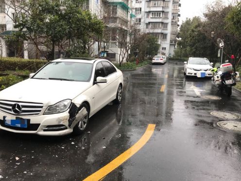 被刮擦的奔驰车,左前侧保险杠和叶子板被撞破,白色外漆掉了一地.