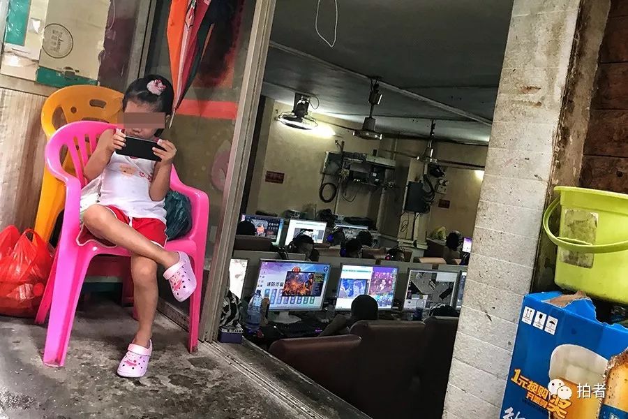 三和人力市场附近的小巷中,网吧老板的孩子在门口玩手机,网吧内生意